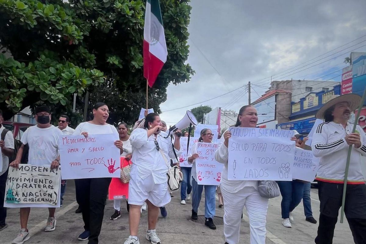 Manifestantes con pancartas y banderas de México marchan por calles del puerto de Veracruz para exigir medicamentos en hospitales.