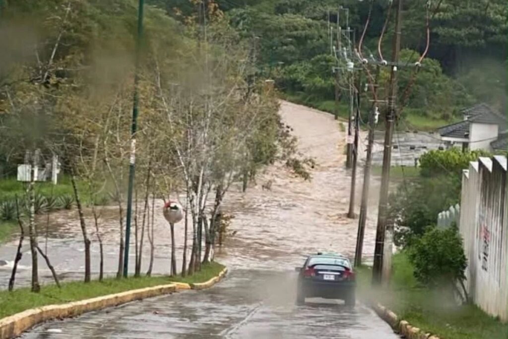 Corriente de agua cubre una calle durante la inundación en Las Fuentes, Xalapa.