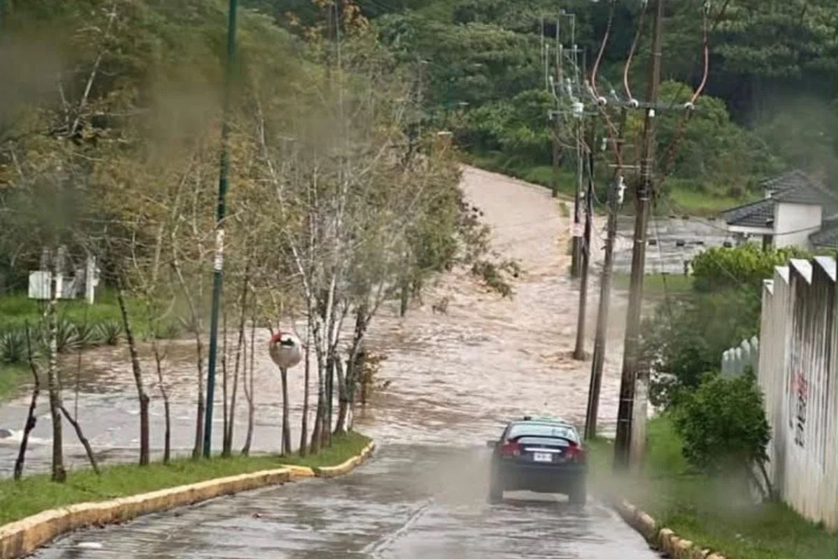 Corriente de agua cubre una calle durante la inundación en Las Fuentes, Xalapa.