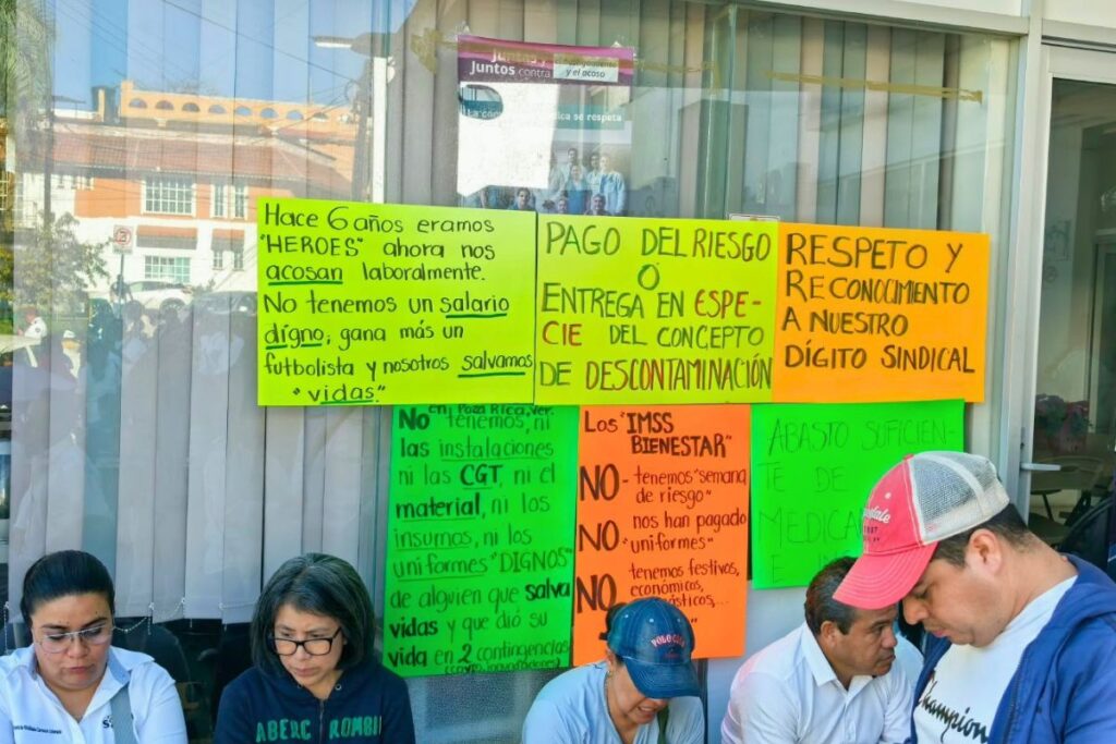 Carteles de trabajadores de IMSS-Bienestar pegados en los ventanales de la Coordinación Estatal en Xalapa.